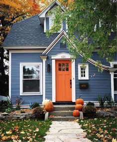 a blue house with orange front door and pumpkins