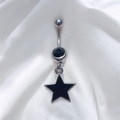 a black and white star belly button ring on a white sheet with a silver ball