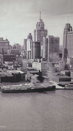 a large boat floating on top of a river next to tall buildings in a city