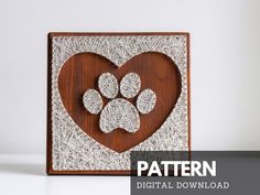 a wooden frame with a dog's paw and heart cut out of it, on top of a white surface