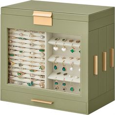 a green cabinet with many pairs of earrings in it's doors and gold handles