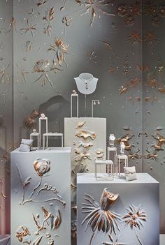 an assortment of decorative items on display in front of a wall with gold leaves and flowers