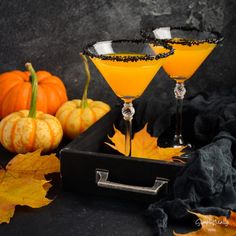 two glasses filled with orange colored liquid and garnished with black speckles