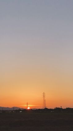 the sun is setting over an open field