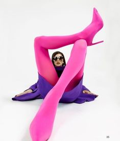 a woman in pink and purple is sitting on the floor with her legs spread out