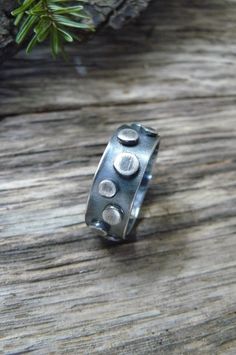 This unisex statement ring is made with 1/4 inch sterling silver in a thick gauge making the piece very sturdy. The band is adorned with sterling elements that vary in size The entire piece was oxidized and polished offering an industrial appearance. This piece is perfect for a man or a woman. Upon purchase send me a message with the ring size. Made to order. To make my pieces withstand loving wear and the test of time, each bracelet is made with very thick gauges of sterling silver. Great thoug Unique Stamped Ring Jewelry, Hand Forged Sterling Silver Round Ring, Unique Hand Forged Sterling Silver Rings, Unique Sterling Silver Round Band Ring, Unique Stamped Silver Rings, Unique Everyday Sterling Silver Rings, Sterling Silver Rings With Oxidized Finish, Brutalist Sterling Silver Rings With Oxidized Finish, Adjustable Brutalist Jewelry Gift