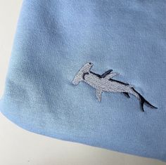 a horse embroidered on the side of a blue t - shirt with white stitching