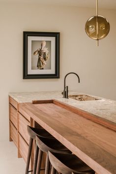 a kitchen with a sink, counter top and framed photograph on the wall above it