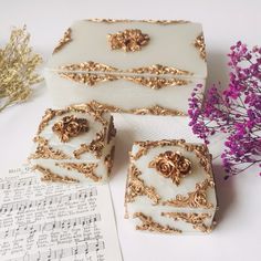 three pieces of cake sitting on top of a table next to music sheets and flowers