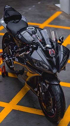 a black motorcycle parked on top of a yellow and white striped parking lot next to a building