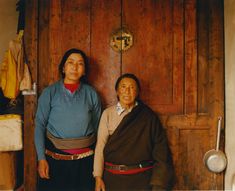 two women standing next to each other in front of a wooden door