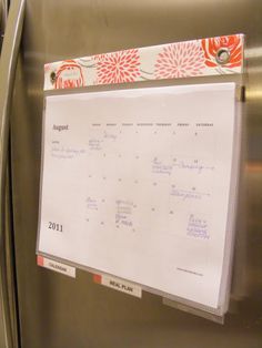 a white board attached to the side of a stainless steel refrigerator with magnets on it