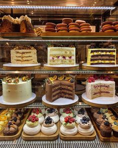 a display case filled with lots of different types of cakes and desserts on top of shelves