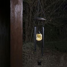 a wind chime hanging from the side of a wooden building with trees in the background