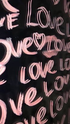 graffiti written on the side of a black wall with pink and white writing that says we love you