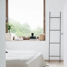 a bedroom with white walls and flooring next to a window overlooking the trees outside