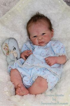 a baby laying on top of a white blanket next to a stuffed animal