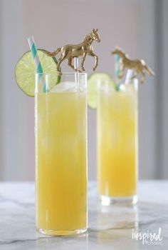 two glasses filled with lemonade, lime and a horse figurine on top