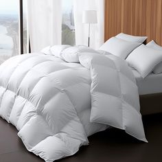 a white comforter on a bed next to a window