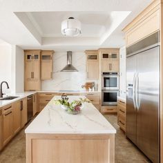 a large kitchen with marble counter tops and stainless steel appliances, along with wooden cabinets