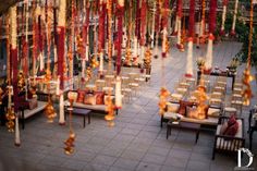 an outdoor wedding venue decorated with red and orange ribbons, hanging from the ceiling over tables