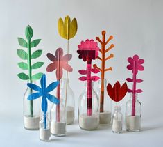 four vases filled with sand and paper flowers