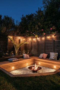 a fire pit surrounded by lights in the middle of a backyard area with wooden fence