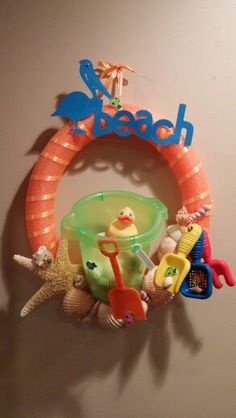 there is a wall decoration with toys hanging on it's side and the word beach spelled out in large letters