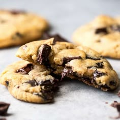 two chocolate chip cookies on top of each other with one broken in half and the rest partially eaten