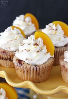 cupcakes with white frosting and orange slices on a yellow cake platter