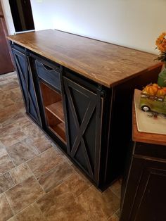 a kitchen with a wooden counter top next to a vase filled with oranges and flowers