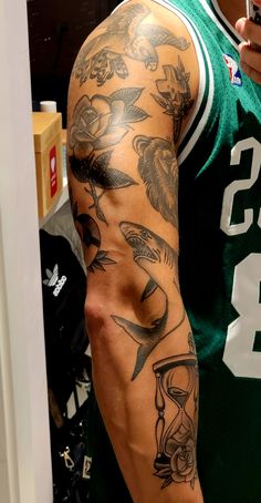 a man with a tattoo on his arm is standing in front of a mirror and wearing a green shirt