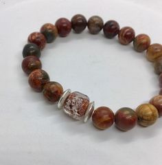 "This unique listing is for a Memorial Cremation Bracelet, made with beautiful 8mm brown, tan green beads. 2 Sterling Silver beads, and one ashes memorial bead. This is a made to order, custom bracelet. A beautiful way to remember your pet. Please contact me for loved ones ashes. I have an average sized wrist of about 6.5 and this fits me great. It is about 7\". Please let me know if you have a small or large wrist, and I can adjust the size for you. Please note: Etsy only allows the sale of Pet Memorial Beads, Cremation Bracelet, Custom Bracelet, Green Beads, Memorial Jewelry, Pet Memorial, Custom Bracelets, Green Bead, Sterling Silver Bead