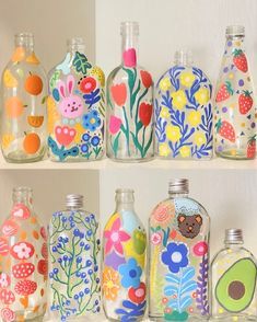 there are many colorful glass bottles on the shelf together, each with different designs and colors