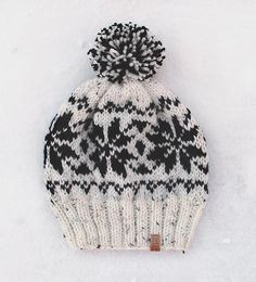 a black and white knitted hat laying in the snow