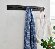 a towel hanging on the wall next to a bag and potted plant in front of a window