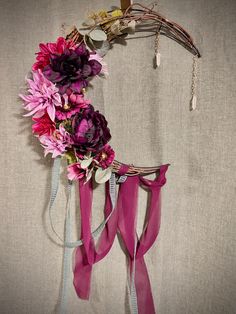 a wreath made out of ribbons and flowers is hanging on the side of a wall