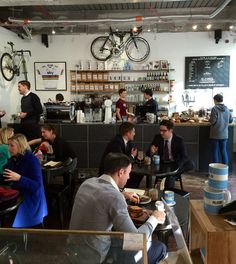 people sitting at tables in a restaurant with bikes hanging from the ceiling and on the walls