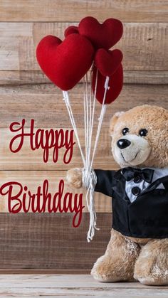 a teddy bear holding two red heart balloons with the words happy birthday written on it