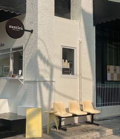 the outside of an eatery with yellow chairs on the sidewalk in front of it