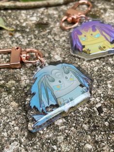 two key chains with cartoon characters on them sitting on the ground next to each other