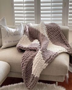 a couch with a blanket on top of it next to two pillows and a pillow