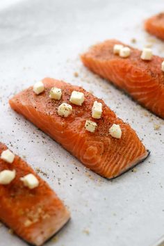 four salmon fillets with garlic and seasoning on top