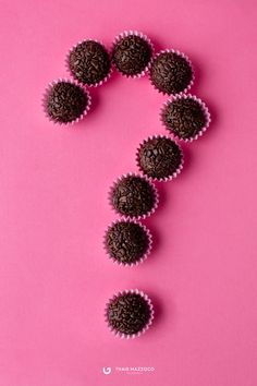 chocolate cupcakes arranged in the shape of a question mark on a pink background