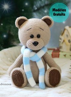 a crocheted teddy bear with a blue and white scarf on it's neck