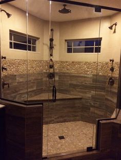 a glass shower door in a bathroom with stone walls and flooring on the outside