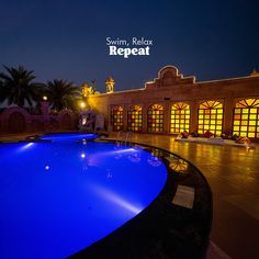 an empty swimming pool in front of a building at night with the words swim relax repeat above it