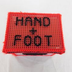 a hand and foot sign is displayed on a white surface with red thread around it