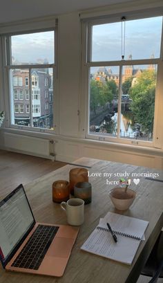 an open laptop computer sitting on top of a wooden table next to a cup of coffee