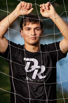 a young man holding his head behind a soccer net